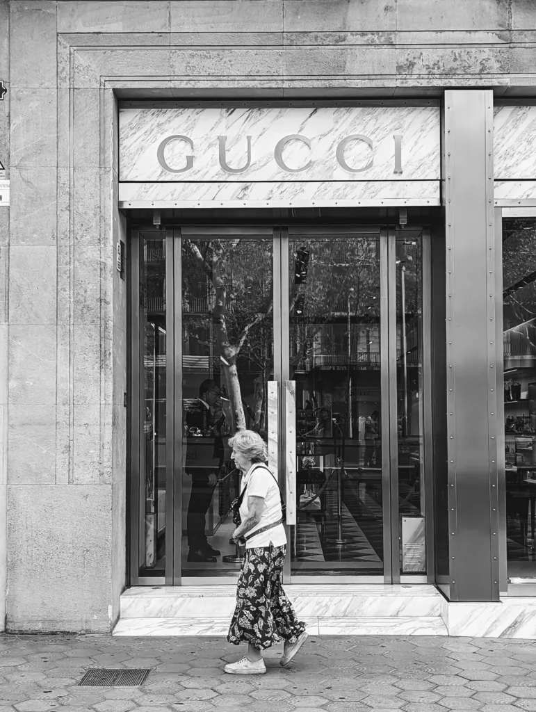 Old lady walks past Gucci shopfront