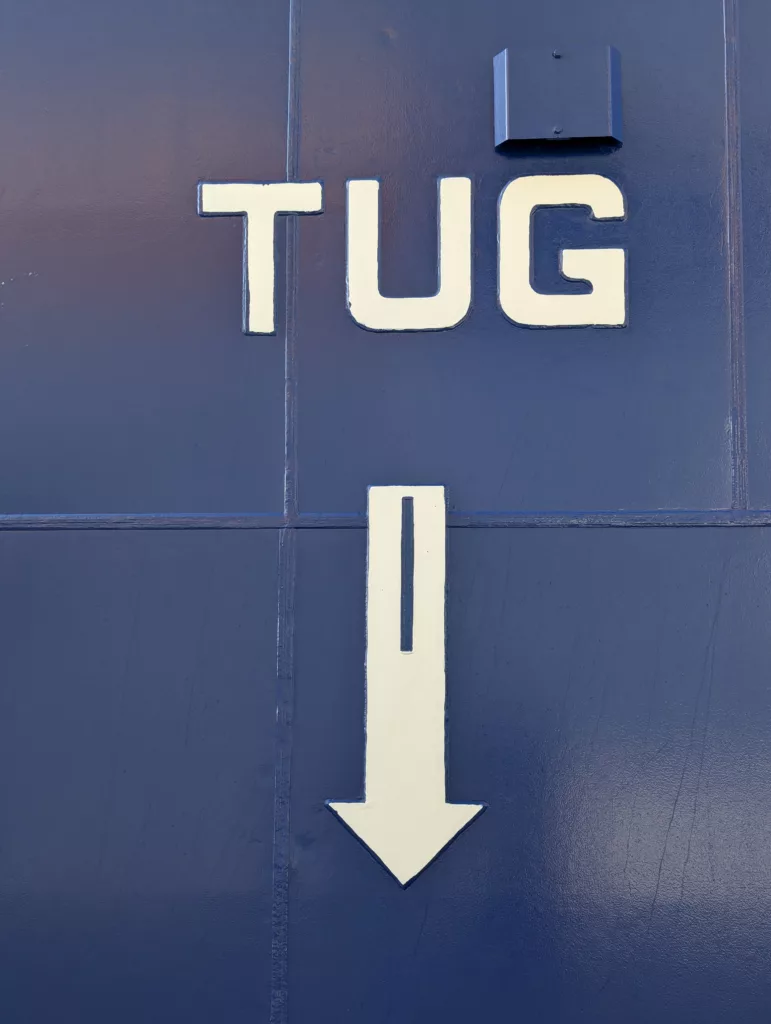 Tug, painted on side of ship with arrow pointing down.