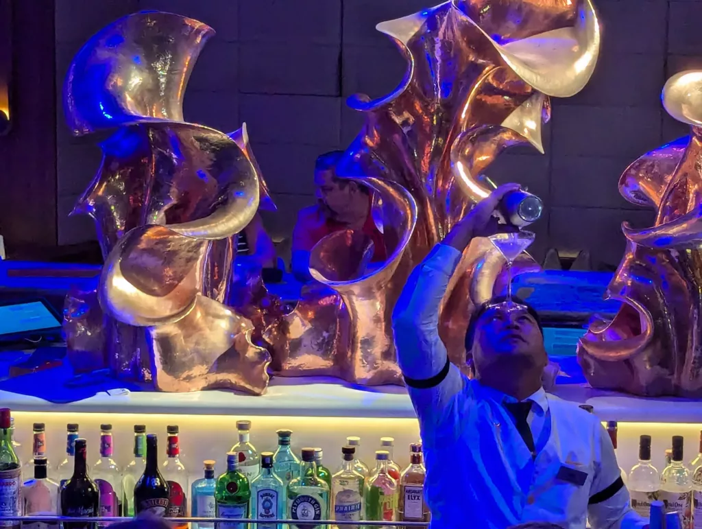Man pouring drink into glass balanced on his forehead