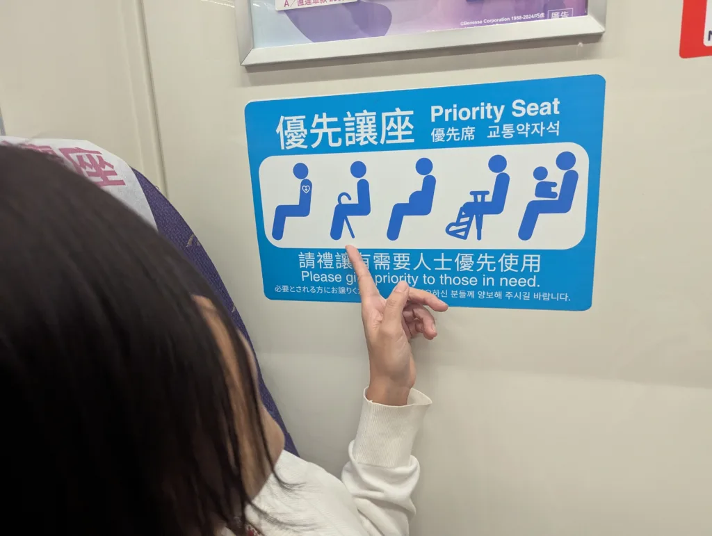 Sachie pointing at disabled seat sticker on train.